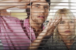 Young business people looking through blinds